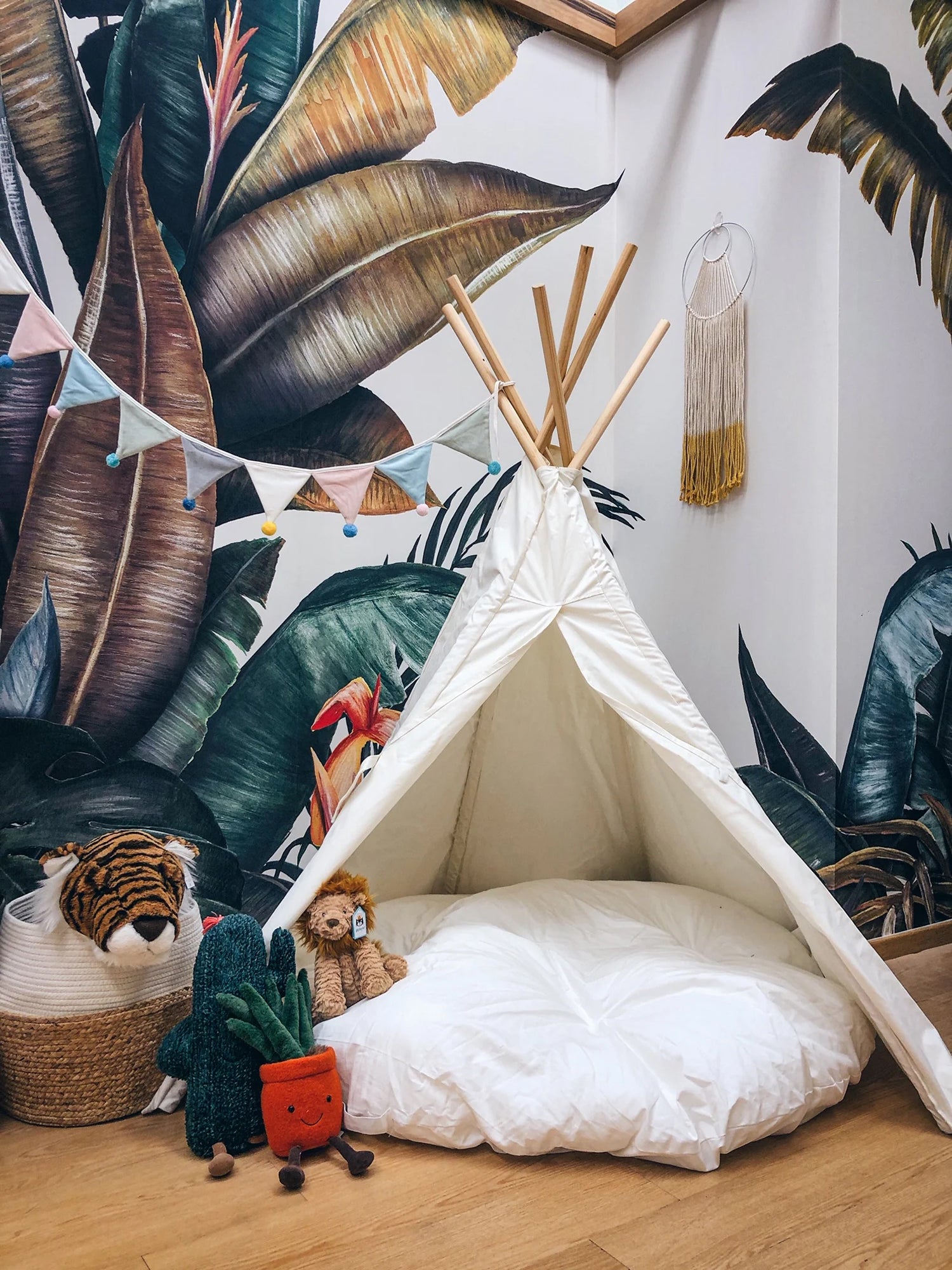 Tropical themed wallpaper in a nursery room with a baby's cot and a kids' tent.