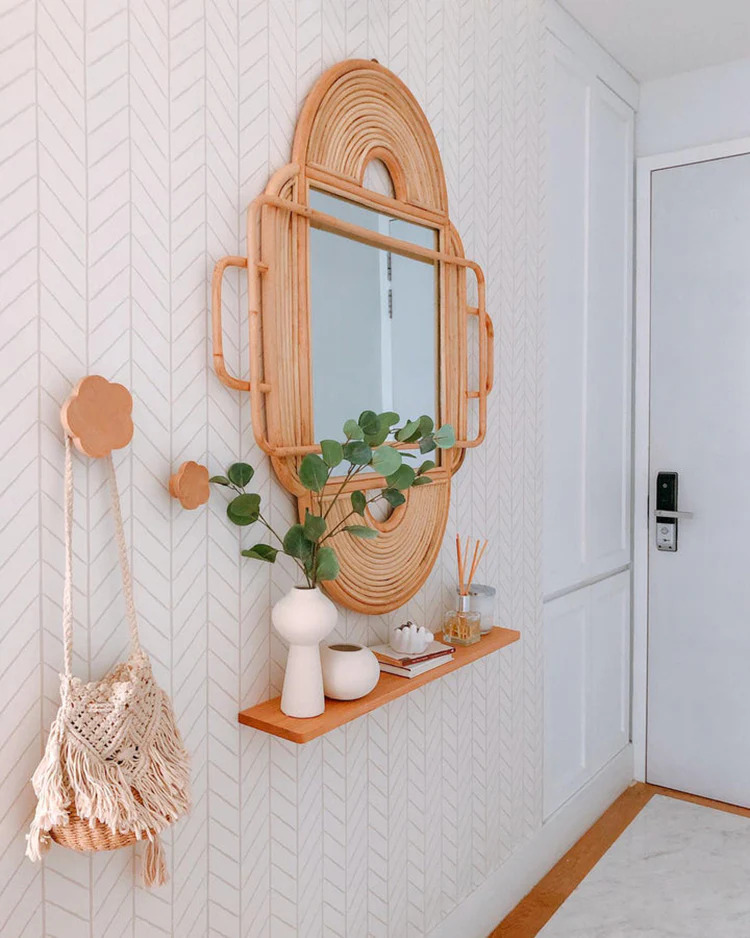 Herringbone Hand-Drawn Wallpaper in a lounge area with light rattan mirror hanging next to the door.