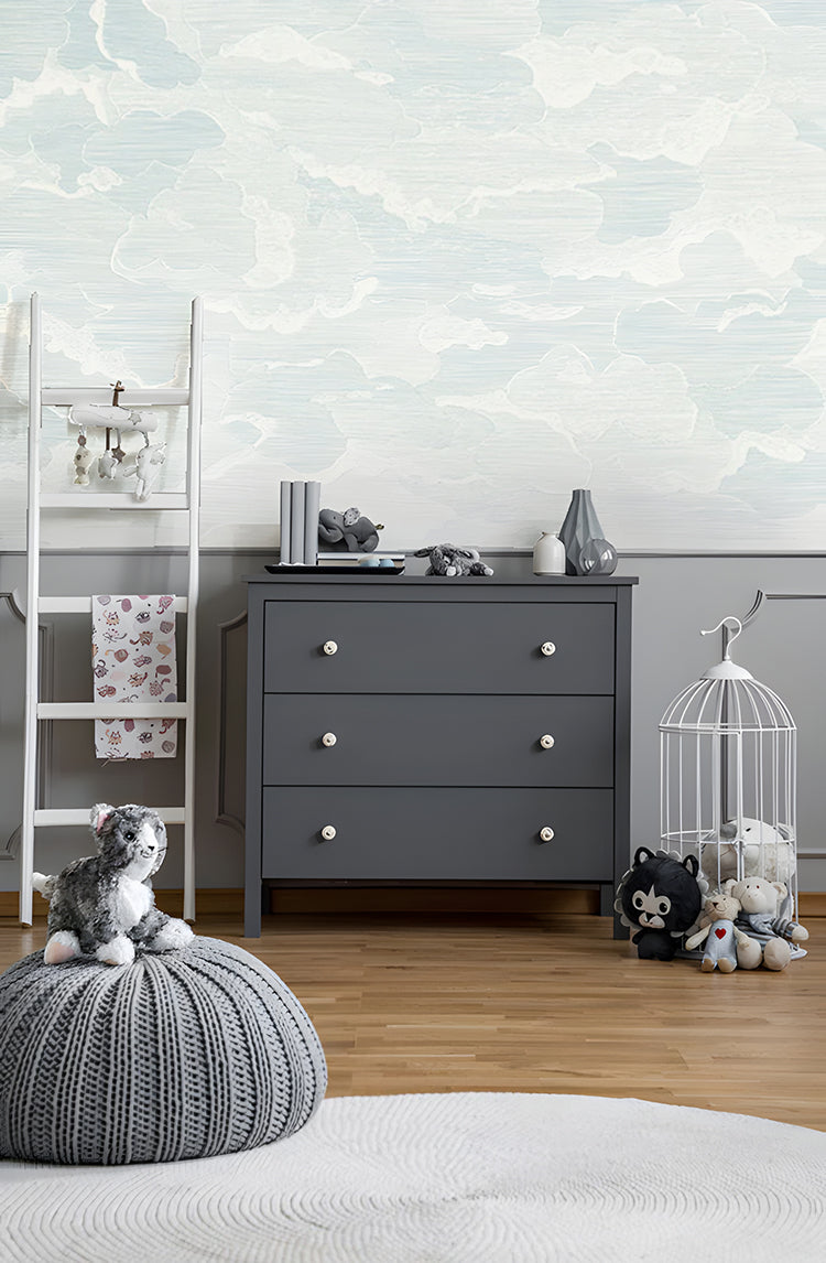 Modern cloud illustration wallpaper accompanies a dark grey sideboard and toys are placed around the floor
